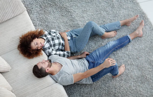 Smiling couple lying on a carpet in a new apartment — Stock Photo, Image
