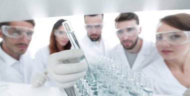 arka plan görüntüsü sıvı cam tüp içinde eğitim microbiologists oluşan bir gruptur.