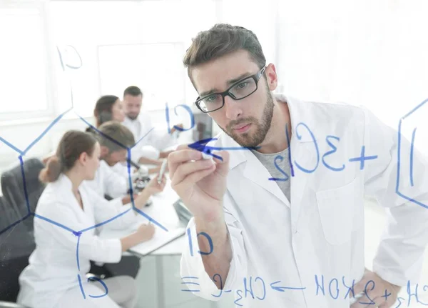 From behind the glass.scientist writes a marker on a glass Board. — Stock Photo, Image