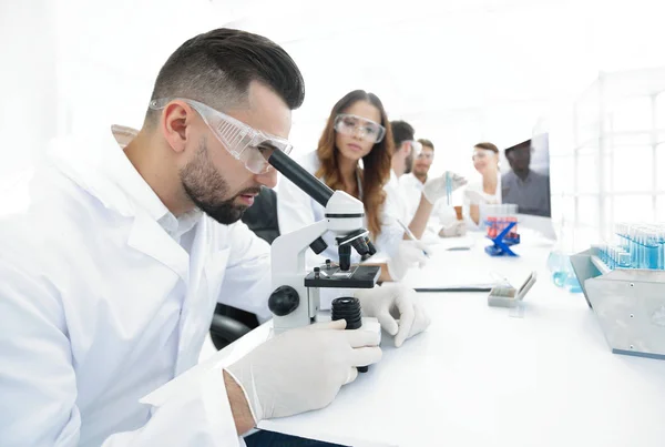 Researcher looking into a microscope in a modern laboratory — Stock Photo, Image