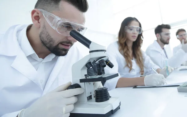 Лаборант мужского пола, рассматривающий образцы в микроскопе — стоковое фото