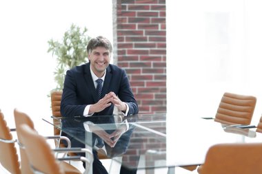 Bir boş konferans salonunda bir masada oturan proje yöneticisi