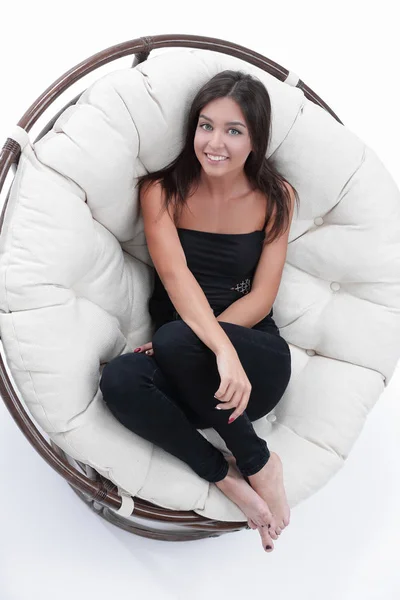 Усміхнена молода жінка відпочиває у великому м'якому кріслі — стокове фото