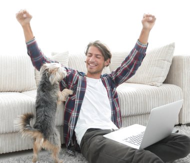 mutlu genç adam köpeğiyle oturma odasında exults