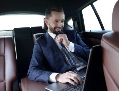 iş adamı arabaya otururken dizüstü bilgisayarda okur