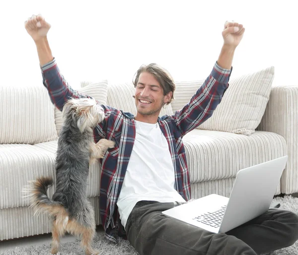 mutlu genç adam köpeğiyle oturma odasında exults