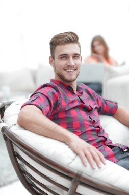 başarılı bir genç adam rahat bir sandalyede oturuyor closeup