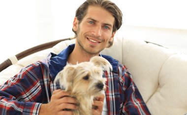 gülümseyen bir adam büyük bir koltukta otururken köpeğini okşayarak Close-Up.