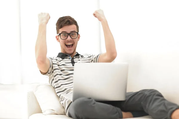 Hombre feliz con el ordenador portátil sentado en el sofá — Foto de Stock