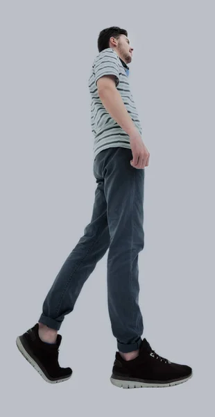 Vista lateral de un joven casual sonriente caminando, sobre un respaldo blanco — Foto de Stock