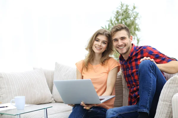 Jovem casal de estudantes com laptop sentado no sofá — Fotografia de Stock