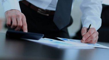 işadamı bir hesap makinesi hesaplamalarını kullanır.