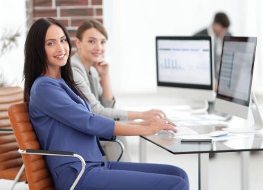 Kameraya bakarak ve oturma işyerinde gülümseyen genç kadın