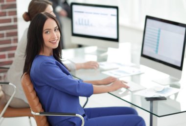 Kameraya bakarak ve oturma işyerinde gülümseyen genç kadın