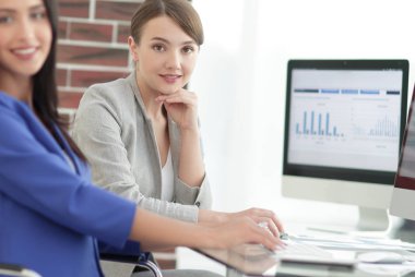 Kameraya bakarak ve oturma işyerinde gülümseyen genç kadın