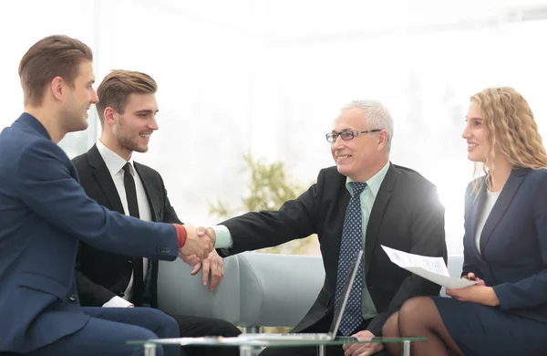 Partners ingår avtal och skakar hand i närvaro av lagmedlemmar — Stockfoto