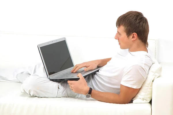 Heel gericht jongeman met behulp van laptop comfortabel zittend. — Stockfoto