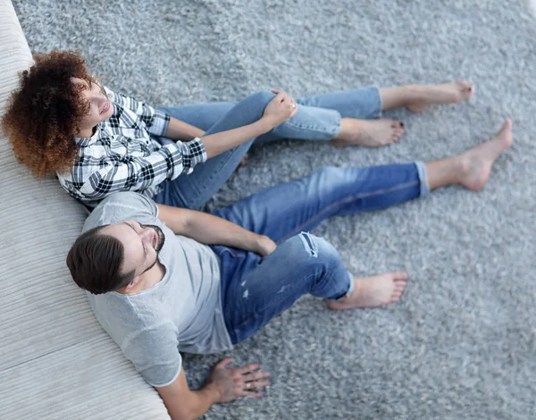 yeni bir oturma odasında bir halı üzerinde oturan yeni evli çift