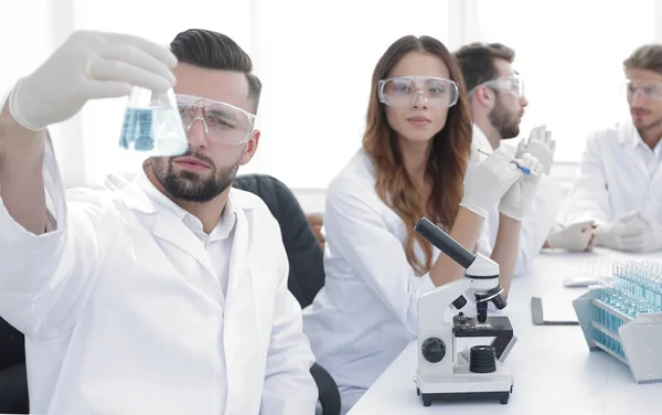 Biochemist with flask Petri sitting at a Desk — Stock Photo, Image