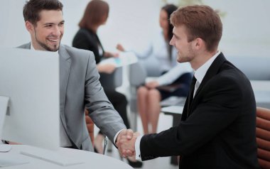 Ofiste otururken el sıkışan iki mutlu genç adam