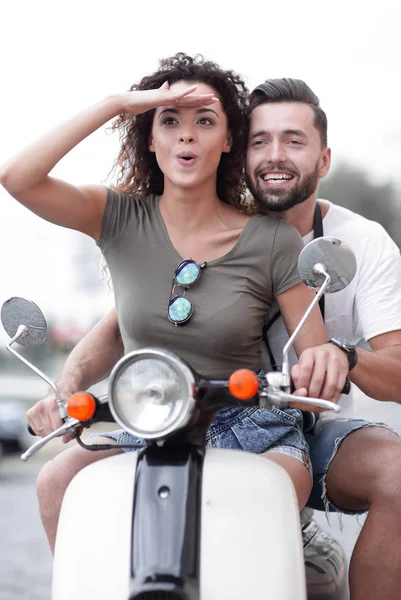 Beautiful young couple is smiling while riding a scooter — Stock Photo, Image