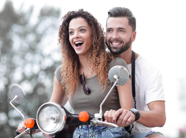 Atractiva pareja montando un scooter en un día soleado en la ciudad — Foto de Stock