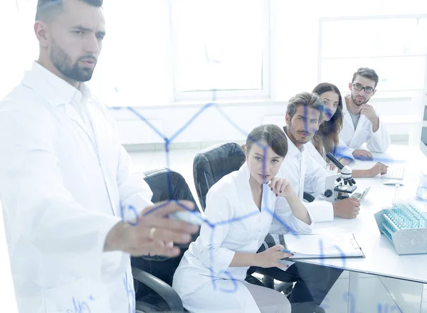 Zza szyby. naukowcem, stojący w pobliżu tablica w laboratorium. — Zdjęcie stockowe