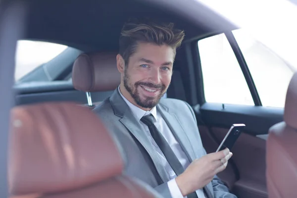 Hombre de negocios sonriendo mientras está sentado en el asiento trasero en el coche —  Fotos de Stock