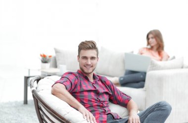 genç erkek büyük bir sandalyede oturuyor gülümseyen