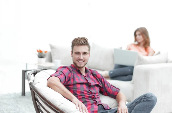 Genç erkek büyük bir sandalyede oturuyor gülümseyen — Stok fotoğraf