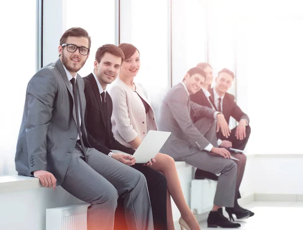 Business team sitting on the windowsill in the new office — Stock Photo, Image
