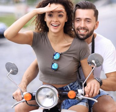 Güzel genç bir çift bir scooter sürme sırasında gülümsüyor