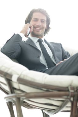 iş adamı rahat bir sandalyede otururken Smartphone'da konuşuyor.