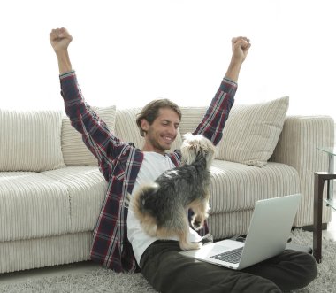 geniş bir oturma odasında otururken köpeğiyle mutlu adam