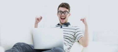 Diz üstü parlak oturma odasında kullanan mutlu genç adam.