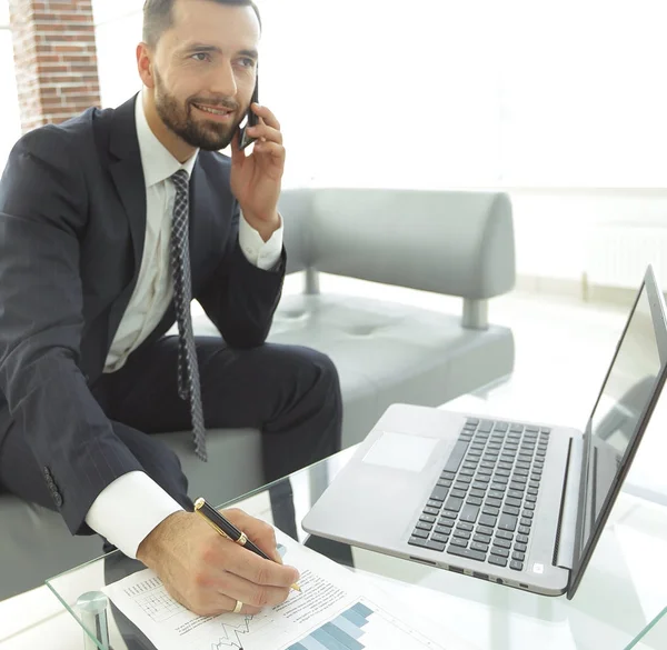 Empresário falando no smartphone sobre gráficos financeiros . — Fotografia de Stock