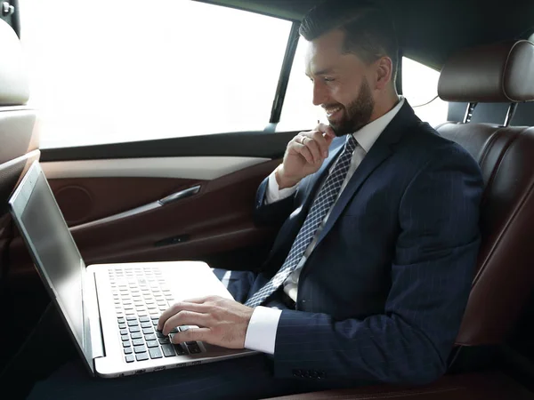 Uomo d'affari digitando testo sul computer portatile mentre seduto in auto — Foto Stock