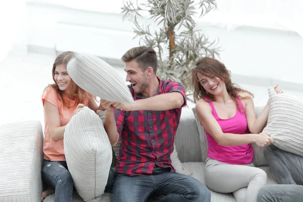一群朋友玩枕头大战，坐在沙发上 — 图库照片