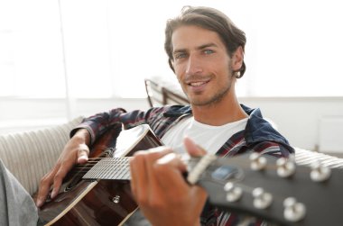 gitar oturma odasında kanepede oturan adam. bir yaşam tarzı kavramı