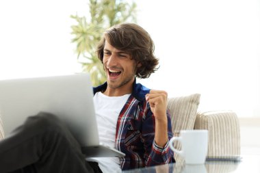 bir sehpa oturan bir dizüstü bilgisayar ile çok mutlu adam.