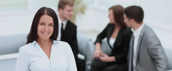 Успішна бізнес-леді стоїть зі своїм персоналом на задньому плані — стокове фото