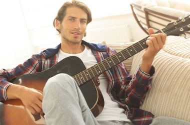 oturma odasında kanepede oturup gitar ile Modern adam.