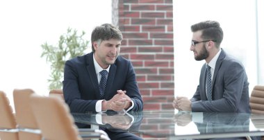 iki işadamı görevleri Office masada oturan tartışıyor.