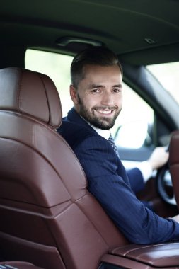 Kameraya bakarak bir arabanın ön koltuğunda otururken yakışıklı genç