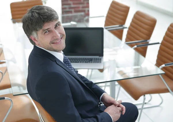 Gerente sorrindo sentado na mesa de trabalho na sala de reuniões . — Fotografia de Stock