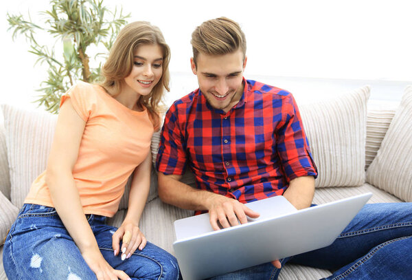 Счастливая современная пара серфингирует в сети и работает на ноутбуке дома