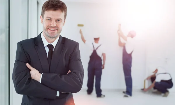 Retrato de um proprietário sorridente. contra o pano de fundo de uma equipe de construtores — Fotografia de Stock