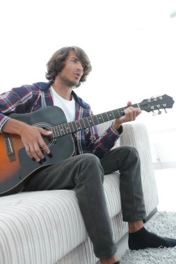 adam bir şarkı söyler ve kanepede oturan gitar çalar.