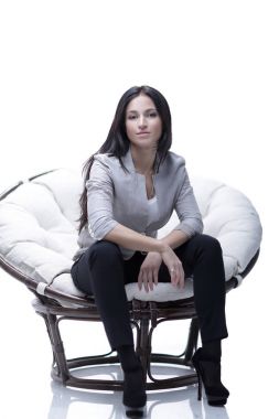 Genç kadın bir yuvarlak rahat yumuşak büyük sandalyede oturuyor.