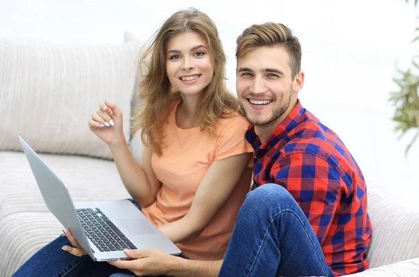 Par de estudantes com um laptop sentado no sofá — Fotografia de Stock